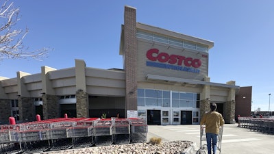 A lone shopper pushes a cart toward the entrance of a Costco warehouse, March 13, 2025, in Sheridan, Colo.