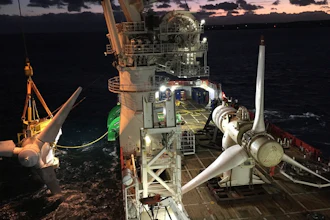 Offshore wind turbine installation vessel at night with turbine blades on deck