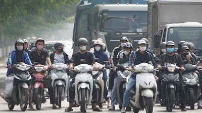 People wearing face masks wait at a traffic signal in Hanoi, Vietnam, on Nov. 14, 2024.
