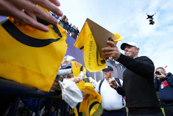 Rory McIlroy of Northern Ireland signs autographs on the 18th green watched by the new Spidercam, top right, following a practice round for the British Open golf championship at the Royal Portrush Golf Club, Northern Ireland, Tuesday, July 15, 2025.