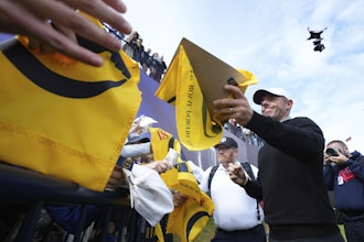 Rory McIlroy of Northern Ireland signs autographs on the 18th green watched by the new Spidercam, top right, following a practice round for the British Open golf championship at the Royal Portrush Golf Club, Northern Ireland, Tuesday, July 15, 2025.