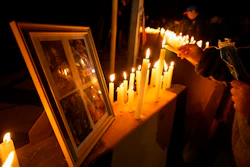 A person lights a candle during a vigil in front of El Teniente copper mine, operated by Codelco, where a cave-in killed six workers, halting operations in Rancagua, Chile, Saturday, Aug. 2, 2025.