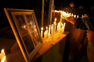 A person lights a candle during a vigil in front of El Teniente copper mine, operated by Codelco, where a cave-in killed six workers, halting operations in Rancagua, Chile, Saturday, Aug. 2, 2025.
