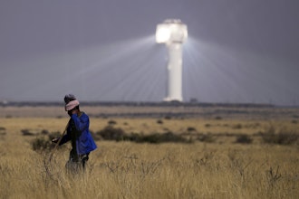 A shepherd watches livestock near Khi Solar One, a solar thermal plant that converts the sun's light energy into electricity, outside Upington, South Africa, in the Northern Cape province, Friday, Aug. 29, 2025.