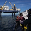 Expedition 501 members look down from the Liftboat Robert platform, to the approaching Gaspee, a crew transport vessel, in the North Atlantic, Saturday, July 19, 2025.