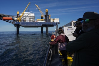 Expedition 501 members look down from the Liftboat Robert platform, to the approaching Gaspee, a crew transport vessel, in the North Atlantic, Saturday, July 19, 2025.