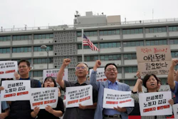 Protesters stage a rally against the detention of South Korean workers during an immigration raid in Georgia, near the U.S. Embassy in Seoul, South Korea, Tuesday, Sept. 9, 2025. The signs read 'A tariff bomb and workers confinement.'