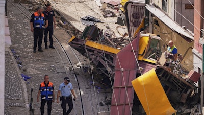 Police officers inspect the site where a tourist streetcar derailed and crashed in Lisbon, Portugal, Thursday, Sept. 4, 2025.