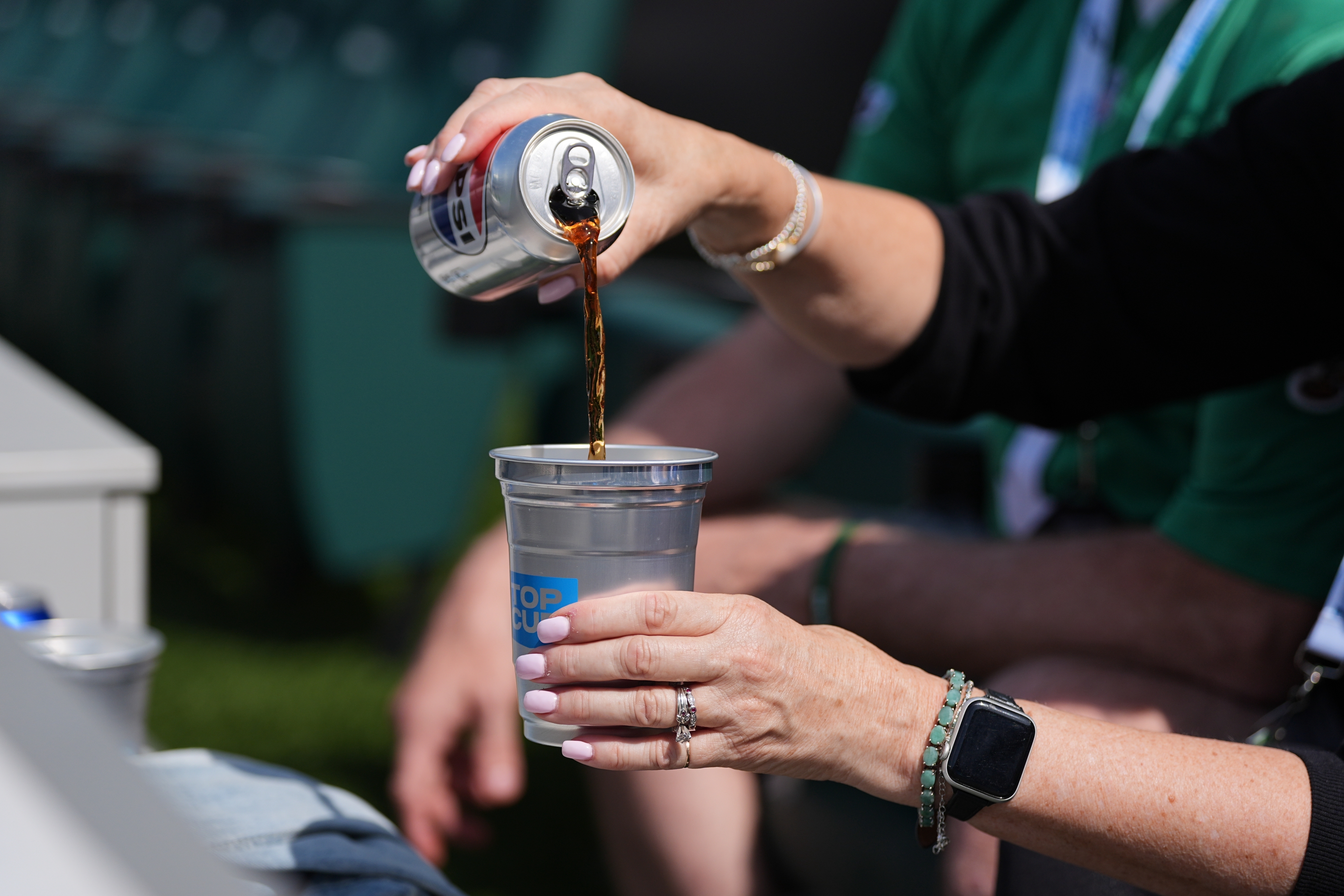 A fan pours a drink into an aluminum cup during an NFL football game in Philadelphia, Sunday, Sept. 21, 2025.
