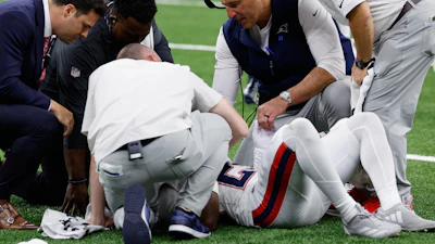 New England Patriots head coach Mike Vrabel, second from right, checks on cornerback Marcus Jones after an injury during the second half of an NFL football game against the New Orleans Saints, Sunday, Oct. 12, 2025, in New Orleans.
