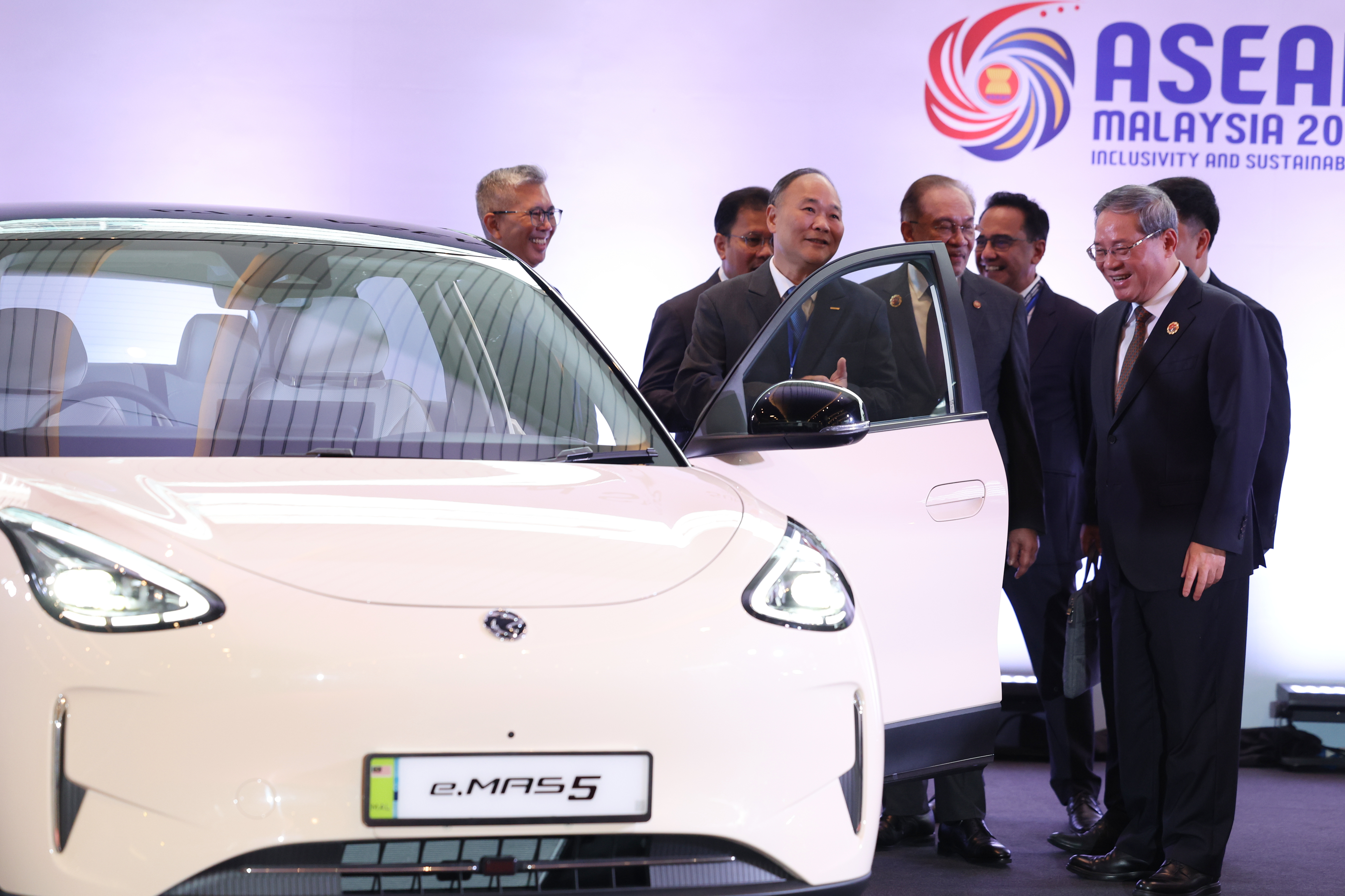 Chinese Premier Li Qiang, right, reacts as he, along with Malaysian Prime Minister Anwar Ibrahim, center, inspects a car produced by Malaysia's national automaker, Proton, in which China's Zhejiang Geely Holding Group holds a 49.9% stake, ahead of the signing ceremony for the ASEAN&ndash;China Free Trade Area 3.0 Upgrade and the ASEAN&ndash;China summit, held as part of the ASEAN summit in Kuala Lumpur, Malaysia Tuesday, Oct. 28, 2025.