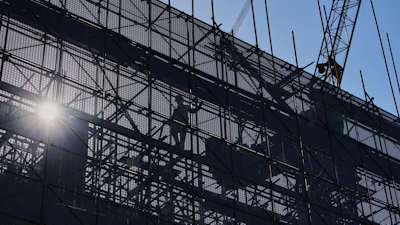 A worker installs scaffolding at a building under construction at the capital popular shopping district, in Beijing, Tuesday, Oct. 21, 2025.