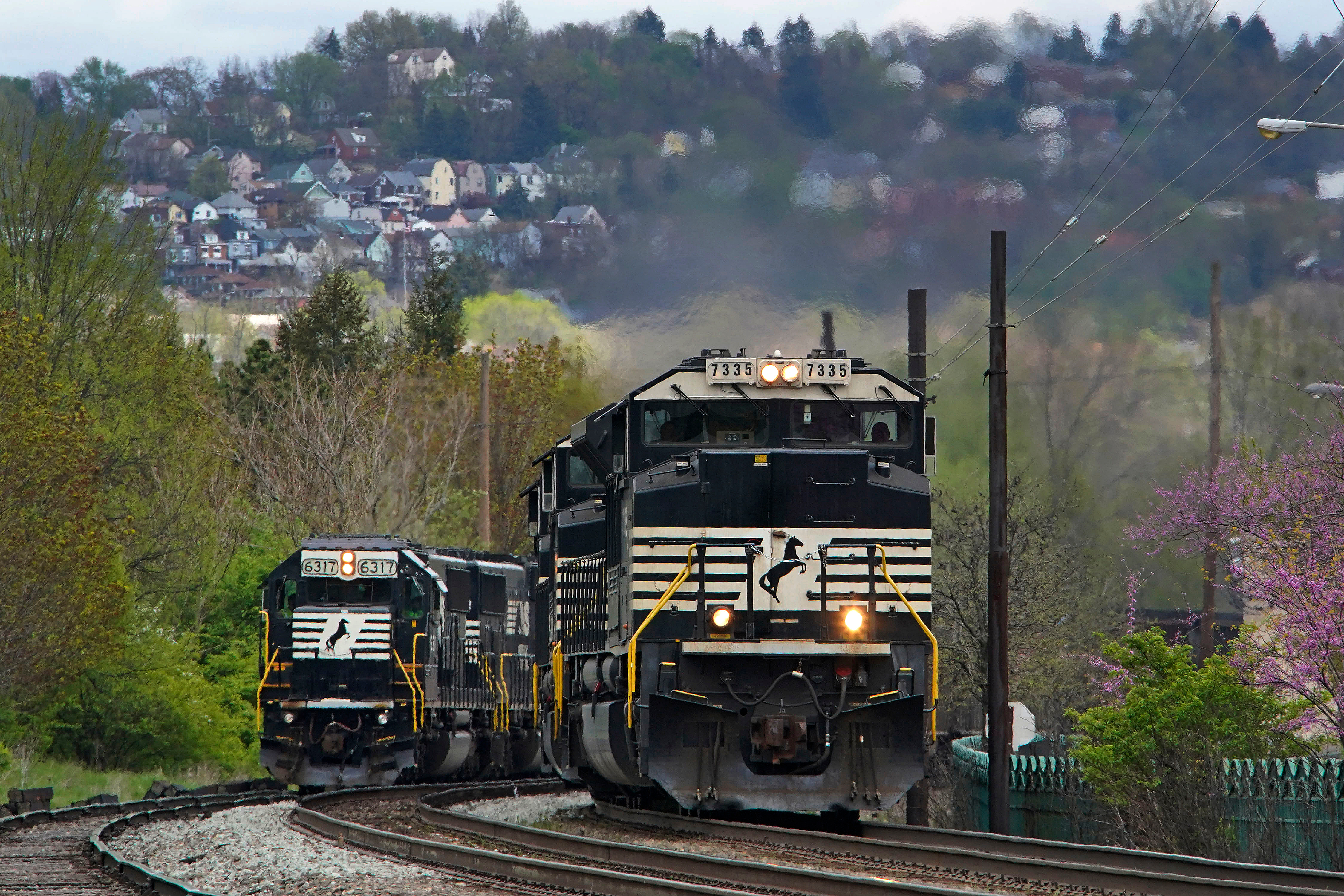 A Norfolk Southern freight train passes a train on a siding as it approaches a crossing in Homestead, Pa, April 27, 2022.