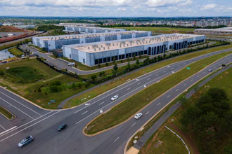 Aerial view of modern corporate campus with white buildings and multi-lane highway