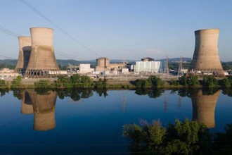 Nuclear power plant with two cooling towers reflected in still water near green landscape