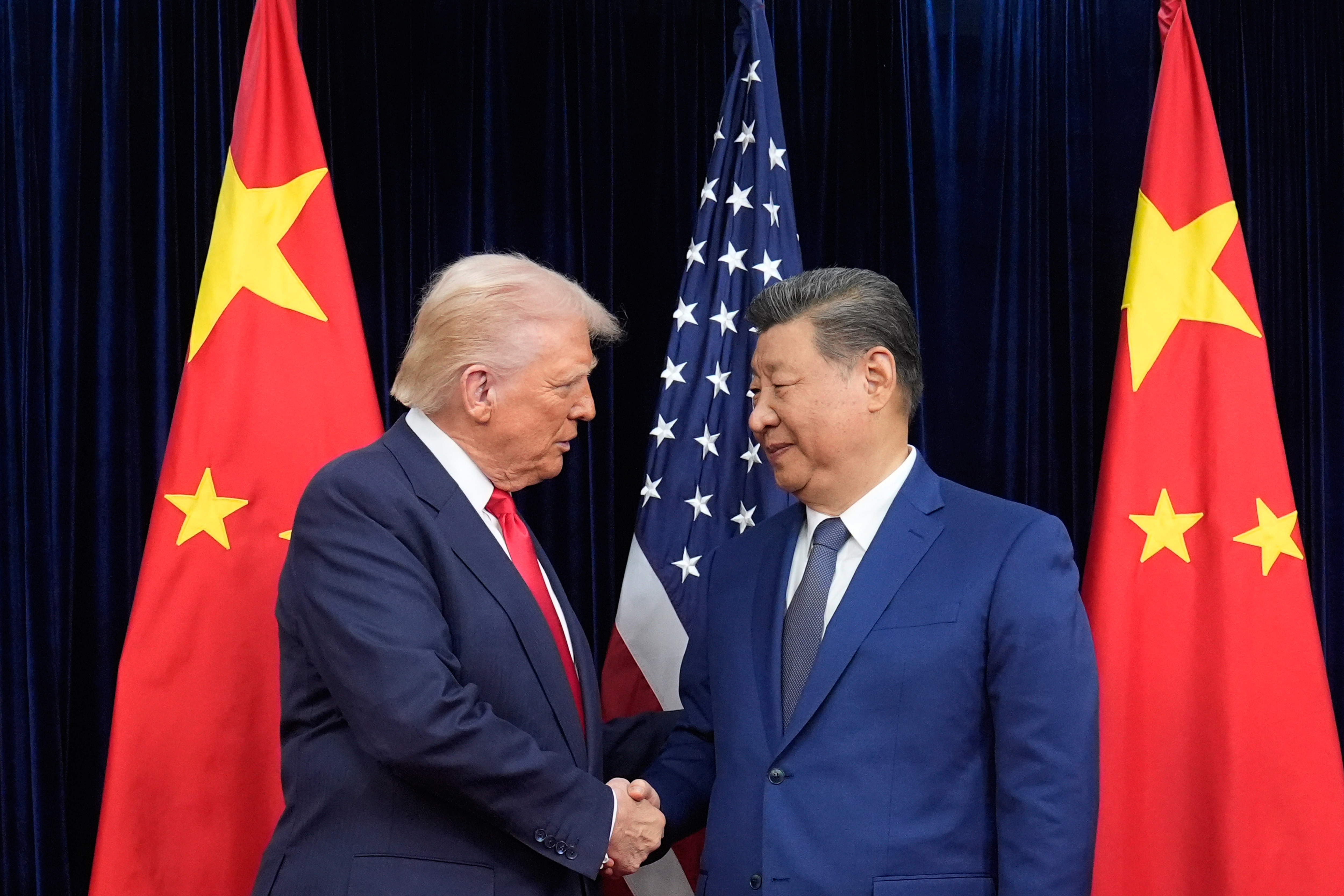 President Donald Trump, left, and Chinese President Xi Jinping, right, shake hands before their meeting at Gimhae International Airport in Busan, South Korea, Thursday, Oct. 30, 2025.