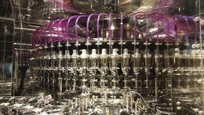 Industrial bottling machine with metallic components and purple tubing