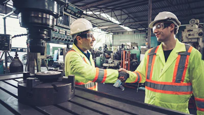 Factory workers shake hands in the factory.