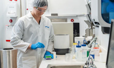 Lab technician in white coat and blue gloves working at scientific research bench