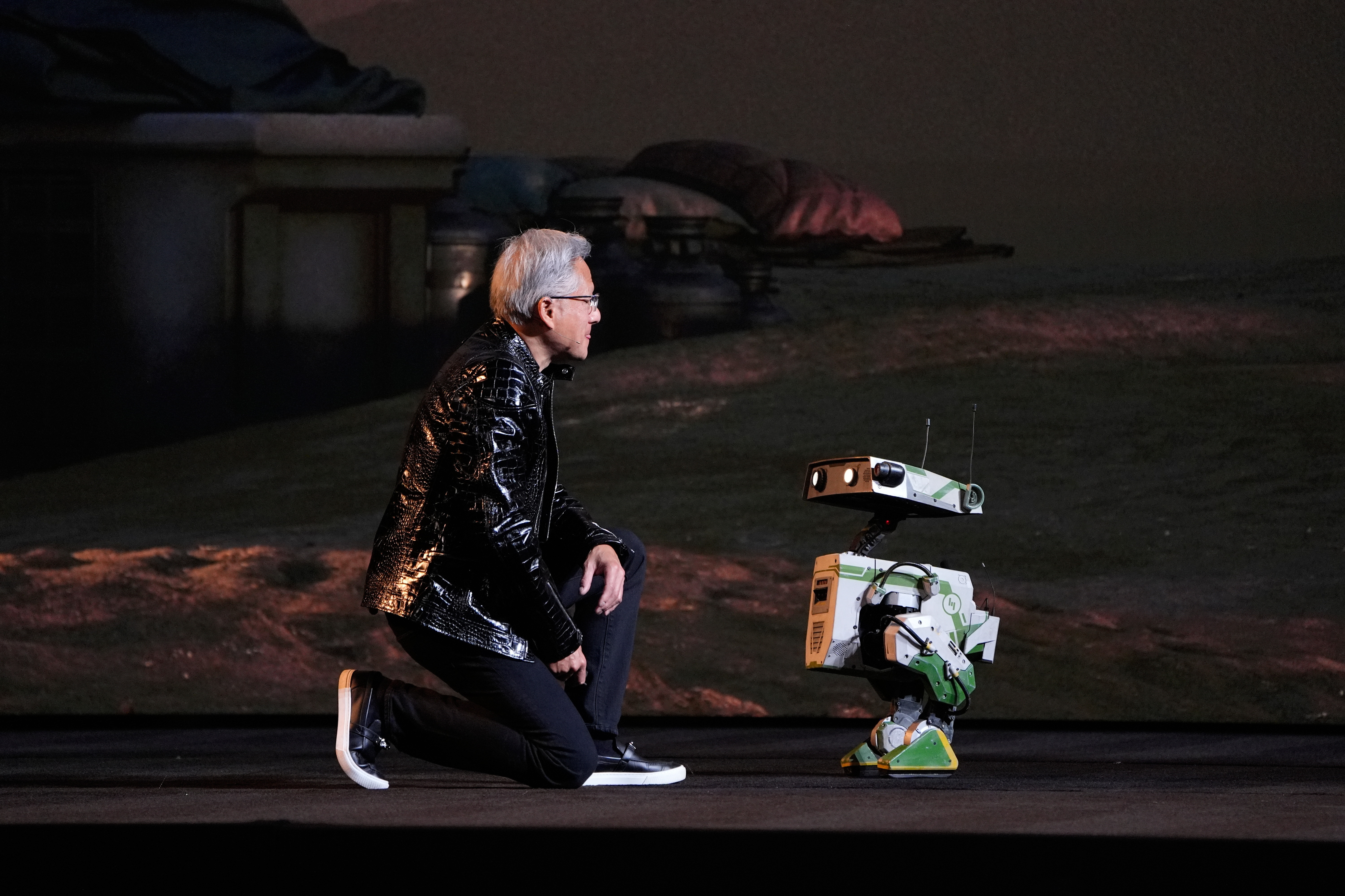 Nvidia founder and CEO Jensen Huang kneels in front of a robot during a Nvidia news conference ahead of the CES tech show Monday, Jan. 5, 2026, in Las Vegas.