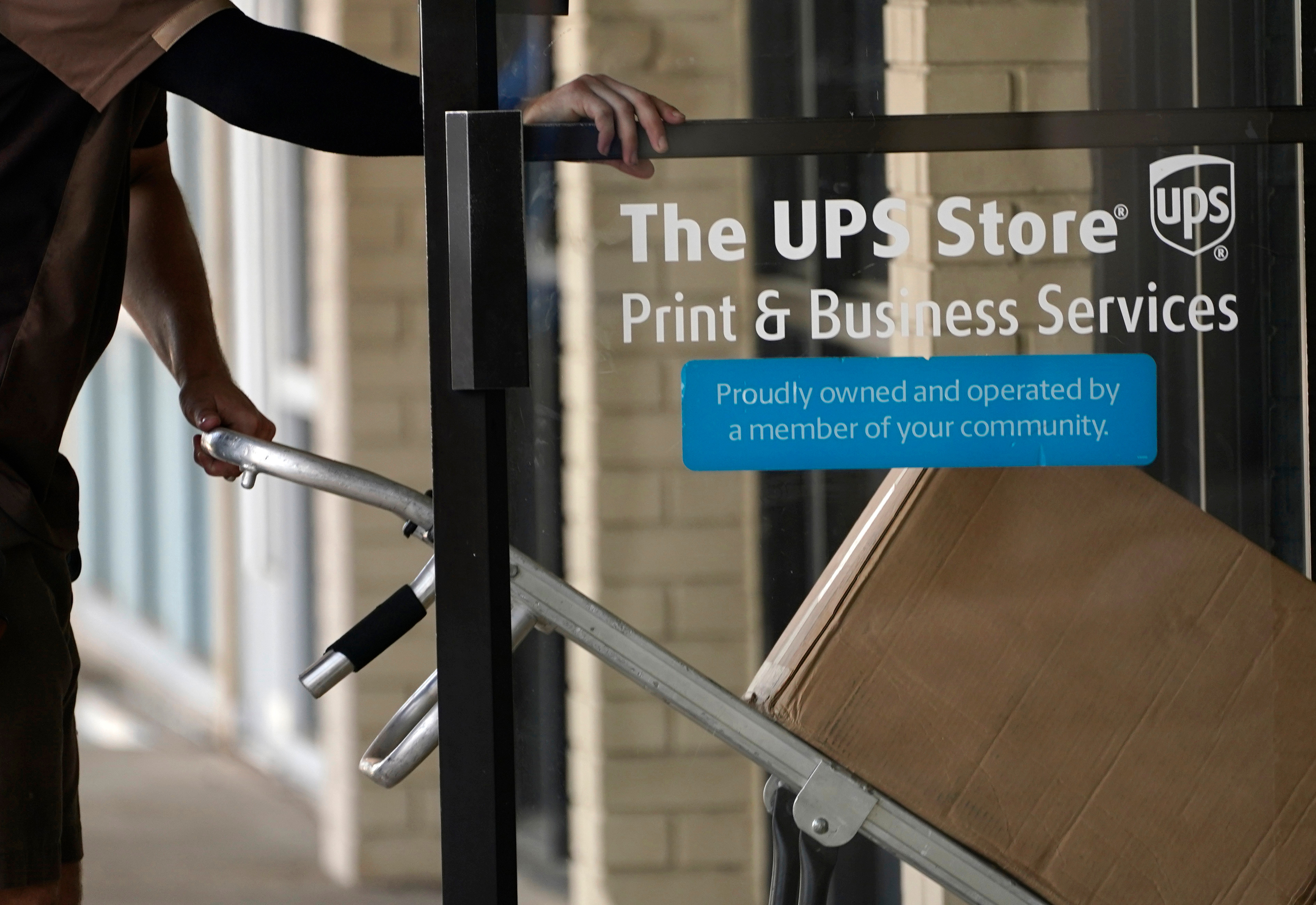 A UPS driver enters a United Parcel Service store with packages in Jackson, Miss., July 26, 2021.