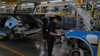 Blue and white car bodies in automotive production line with workers assembling vehicles