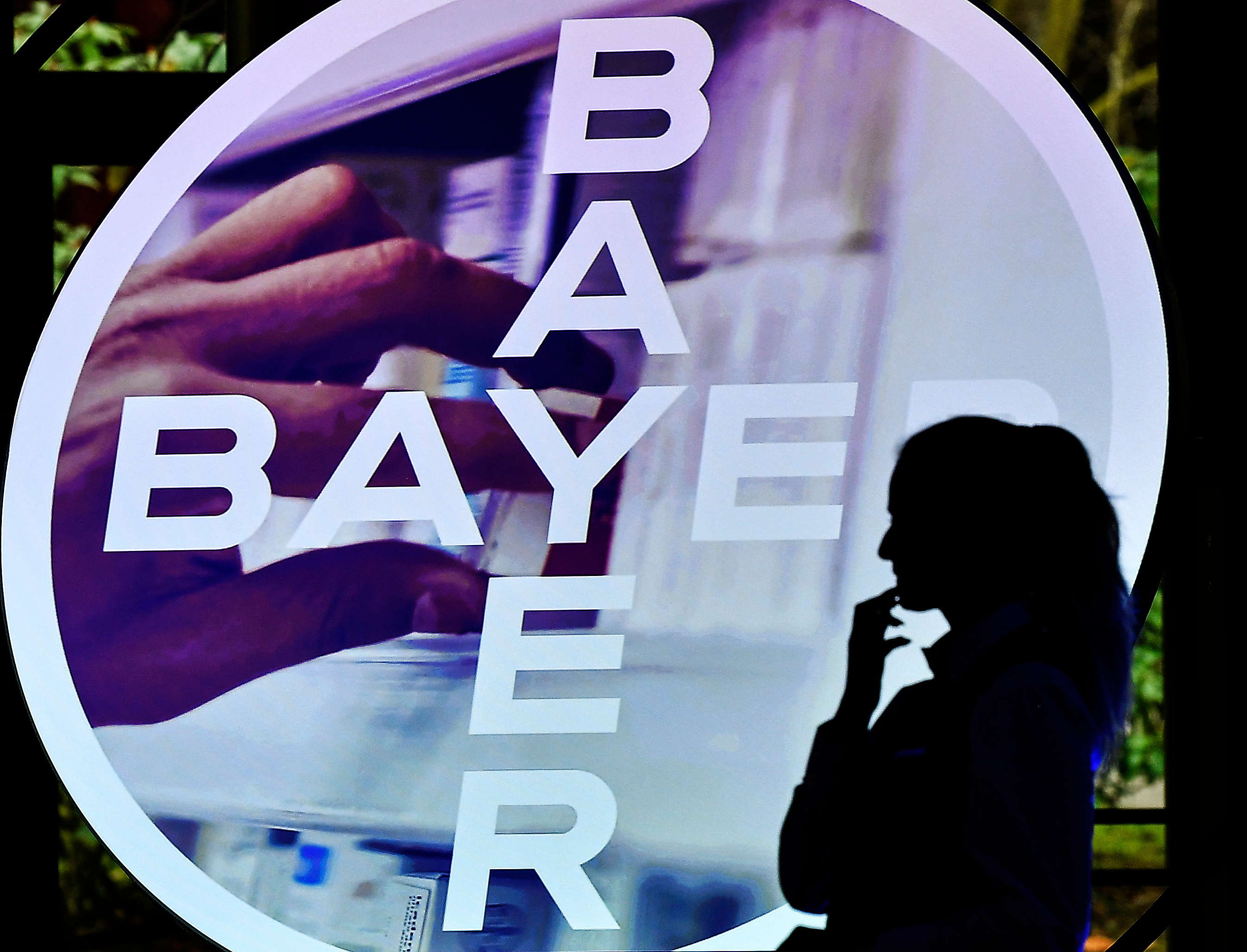 A woman walks in front of a Bayer AG logo at a news conference in Leverkusen, Germany, Feb. 27, 2020.