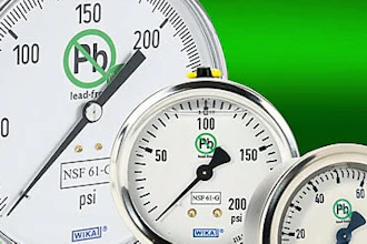 Three industrial pressure gauges with brass fittings on green background