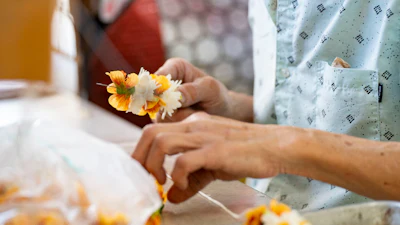 Sam Say, owner of M.P. Lei Shop, strings flowers to make a lei at his shop in Chinatown, Thursday, Feb. 26, 2026, in Honolulu.