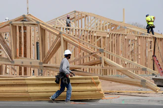 Construction workers install a lumber roof at a new home build Tuesday, April 1, 2025, in Laveen, Ariz.