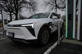 White Chevrolet Bolt EV charging at public electric vehicle charging station with green accents