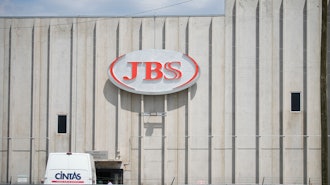 Employees walk in front of the entrance to the JBS meat processing plant, July 23, 2021, in Greeley, Colo.