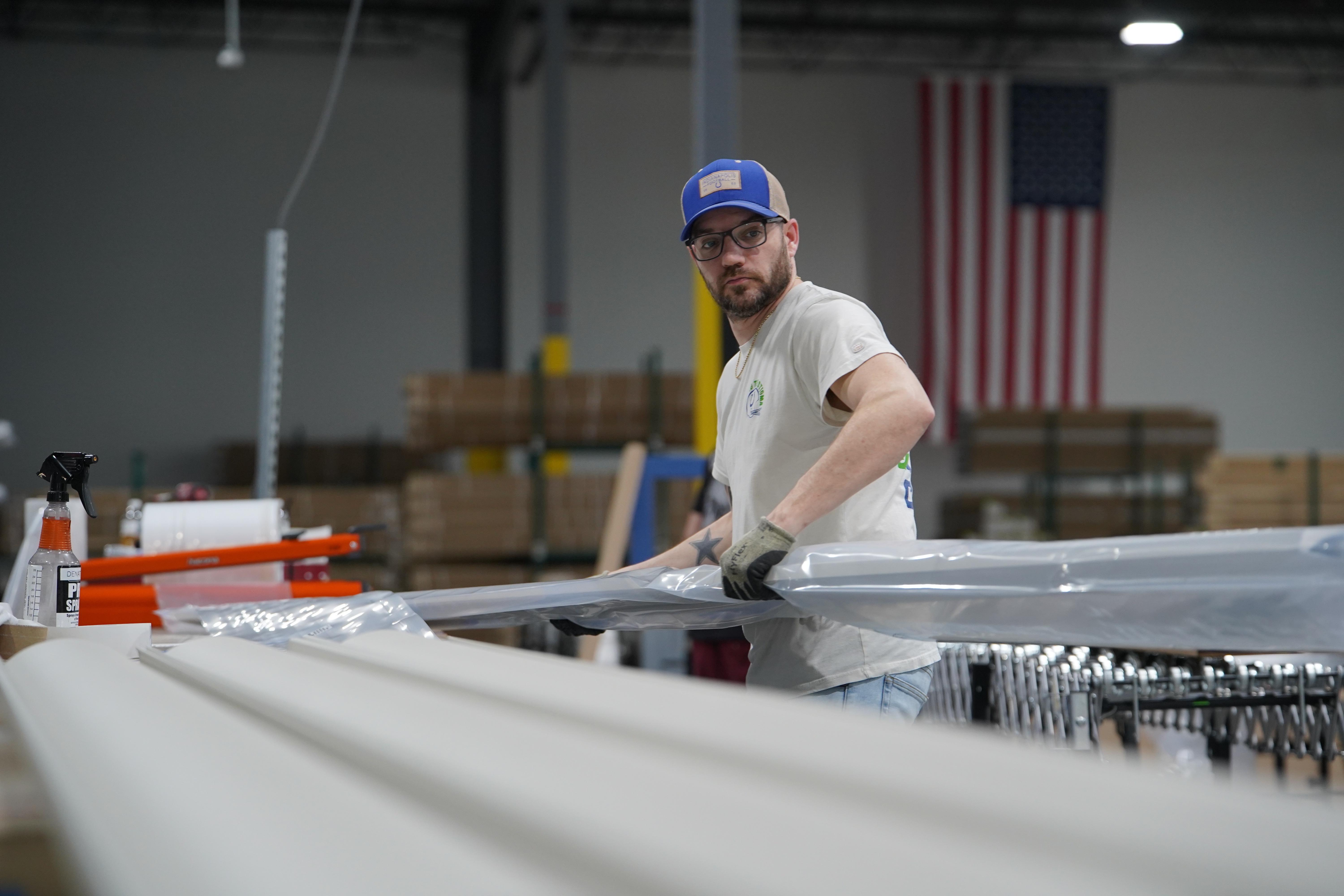 A worker lifts an aluminum beam on the factory floor at The Luxury Pergola, a company that manufactures aluminum pergolas, on Friday, Feb. 20, 2026, in Noblesville, Ind.