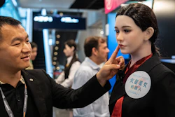 A member of staff touches the face of a humanoid robot showcased at an exhibition in Hong Kong on Monday, April 13, 2026.