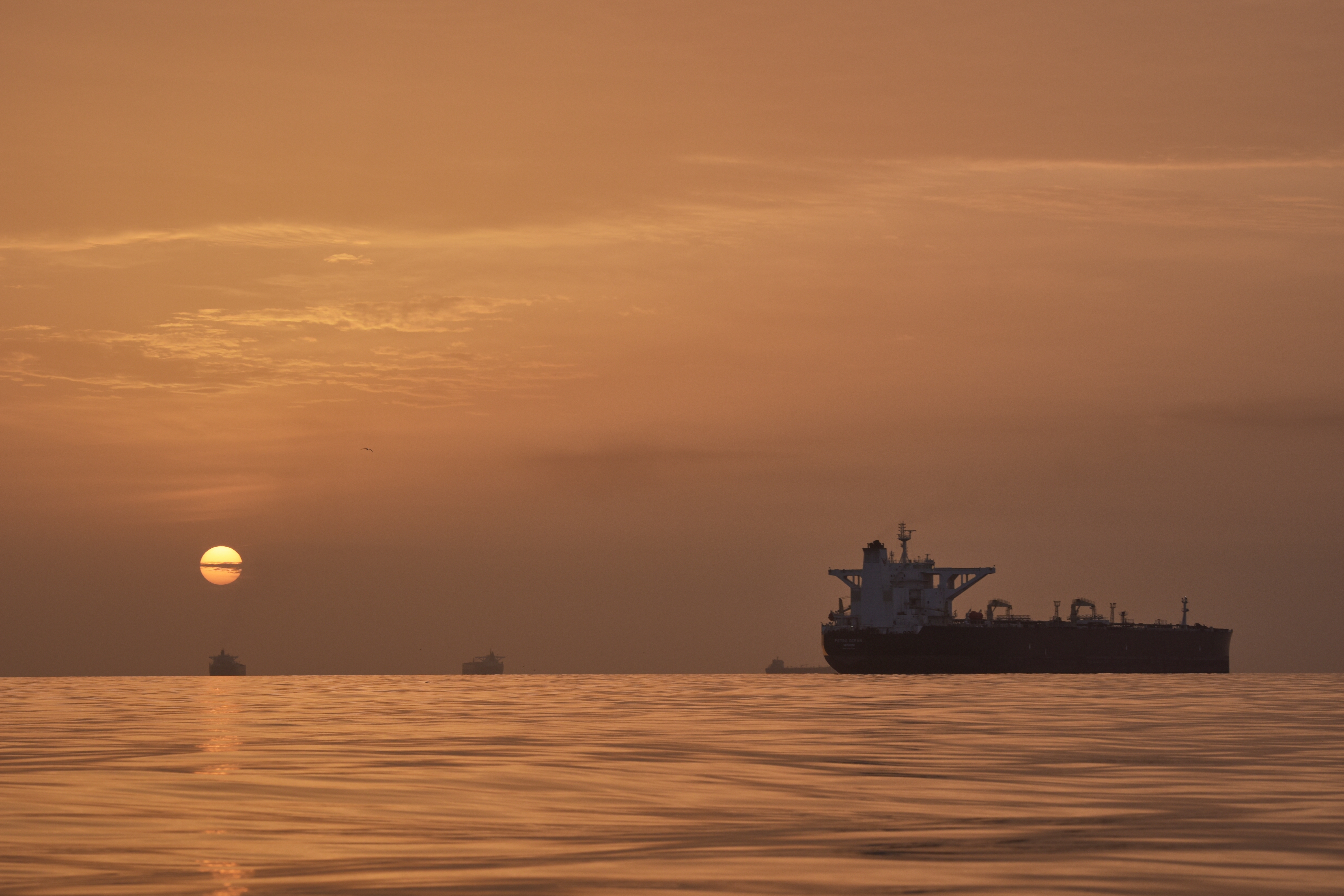 The sun rises behind tankers anchored in the Strait of Hormuz off the coast of Qeshm Island, Iran, April 18, 2026.