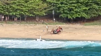 Kauai Ocean Safety members and other people assist individuals after an Airborne Aviation tourist helicopter crash on Kalalau Beach on Kauai, Hawaii, on March 26, 2026.