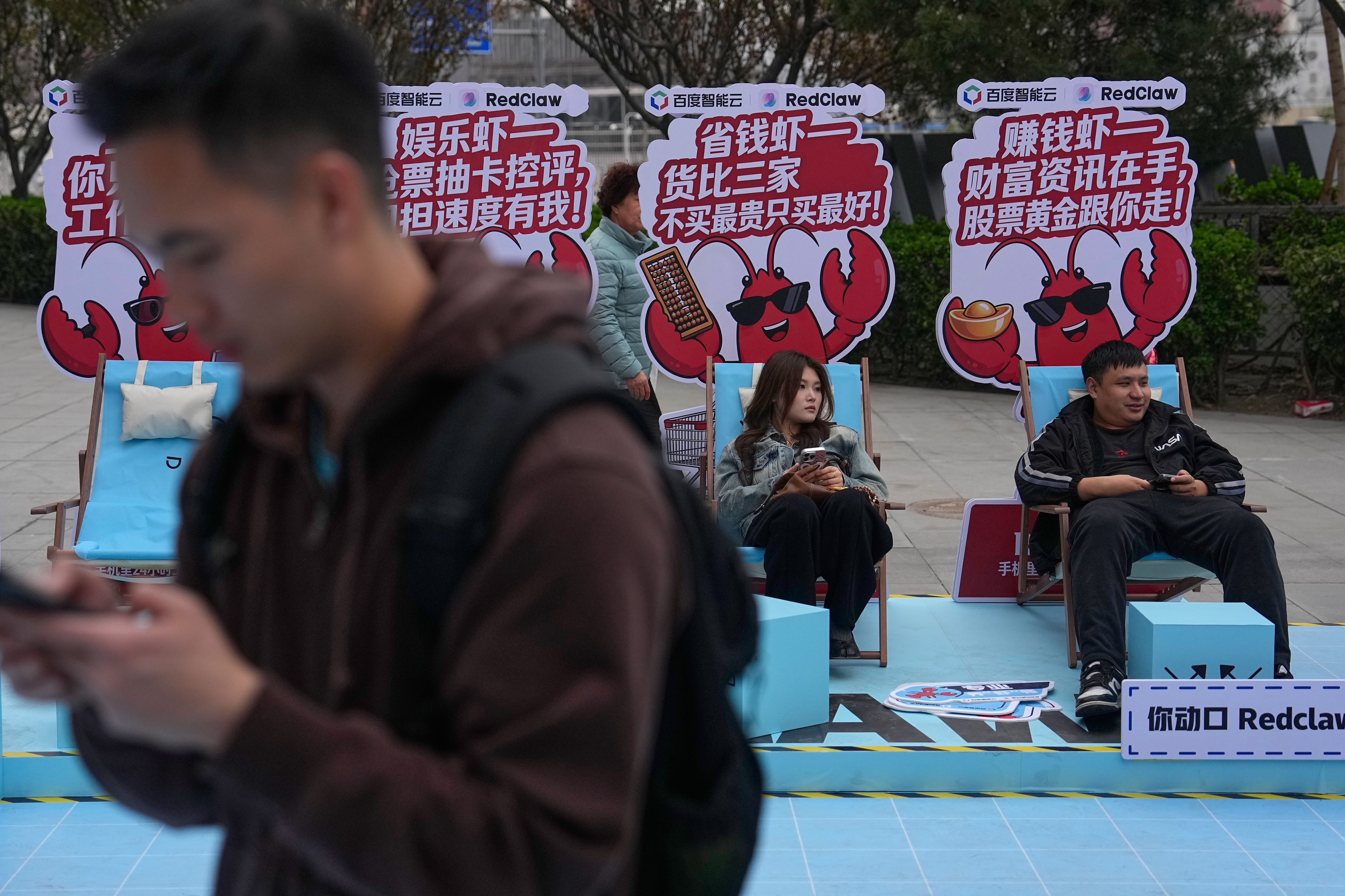 Shoppers rest at a RedClaw AI promotion booth outside a shopping mall in Beijing, March 28, 2026.