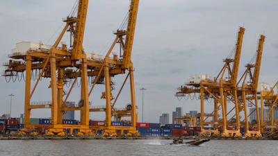 A small boat splashes past a row of ship-to-shore cranes at Khlong Toei Pier in Bangkok, Thailand, Jan 3, 2026.