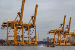 A small boat splashes past a row of ship-to-shore cranes at Khlong Toei Pier in Bangkok, Thailand, Jan 3, 2026.