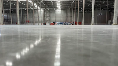 Spacious industrial warehouse with polished concrete floor, metal framework, and glass partitions