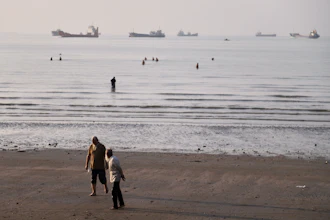 Men walk on the shoreline as people wade in the water in the Strait of Hormuz off Bandar Abbas, Iran, June 1, 2026.