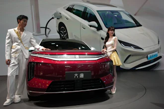 Models stand next to a latest EV car from Chinese automaker BYD showcased at the Auto China 2026, in Beijing, April 25, 2026.