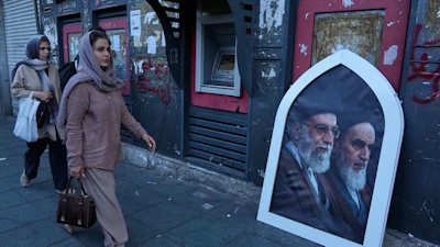 Pedestrians walk past a poster showing slain Iranian Supreme Leader Ayatollah Ali Khamenei, left, and the late revolutionary founder Ayatollah Khomeini, Islamic Revolution square, Tehran, June 14, 2026.