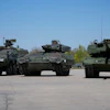 A boxer armoured personnel carrier, from left, a Puma infantry fighting vehicle and a Leopard battle tank are displayed during the opening of a new production line production line of Boxer 8x8 wheeled armoured personnel carrier produced by pan-European defense company KNDS in Munich, Germany, on April 22, 2026.