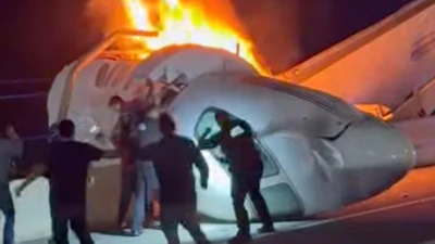 A passenger, top, jumps out of a plane after it crashed on a highway as other people help Tuesday, June 16, 2026, in Laredo, Texas.