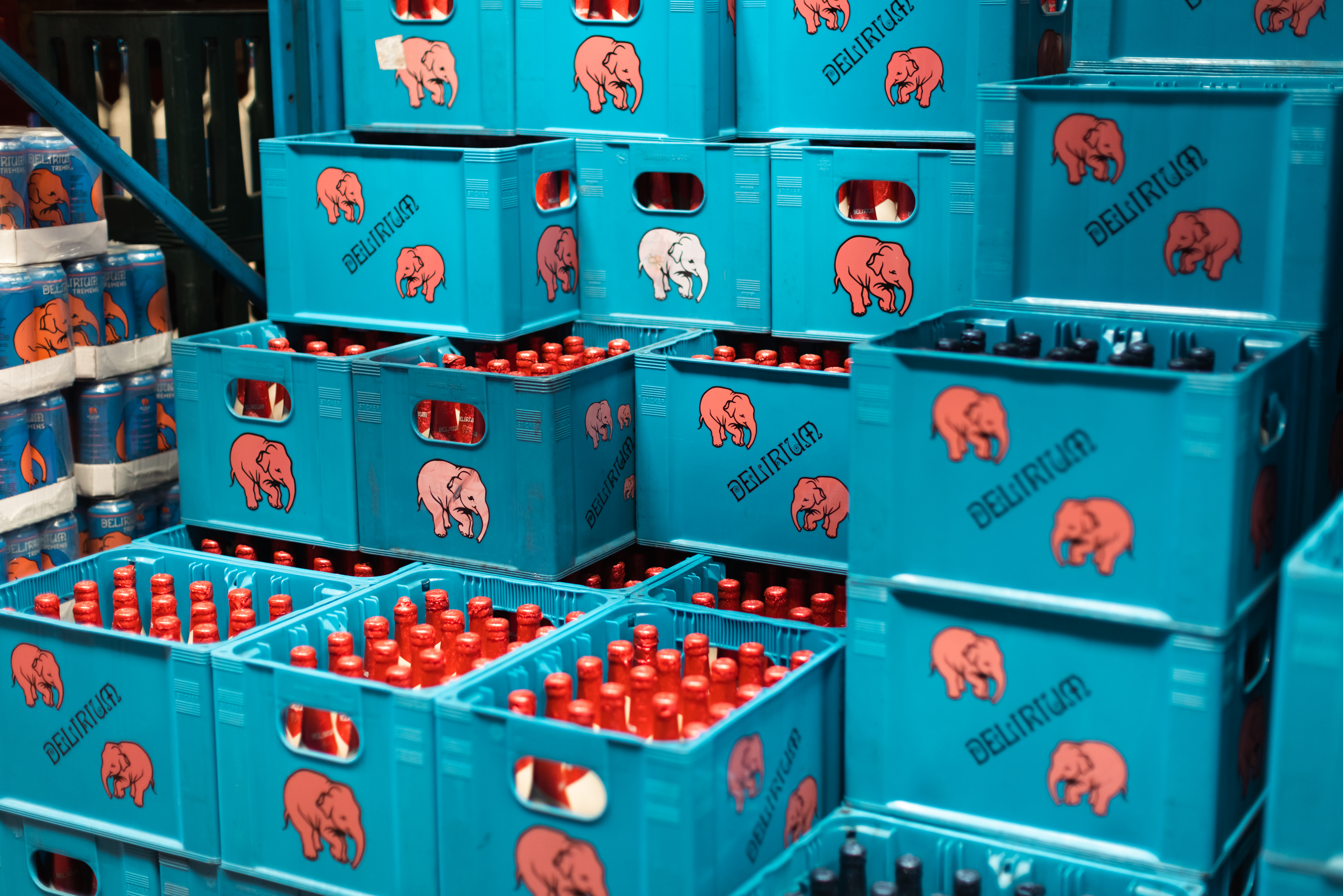 Stacked turquoise Delirium beverage crates with red bottles stored in warehouse setting