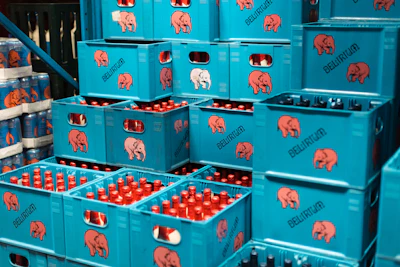Stacked turquoise Delirium beverage crates with red bottles stored in warehouse setting