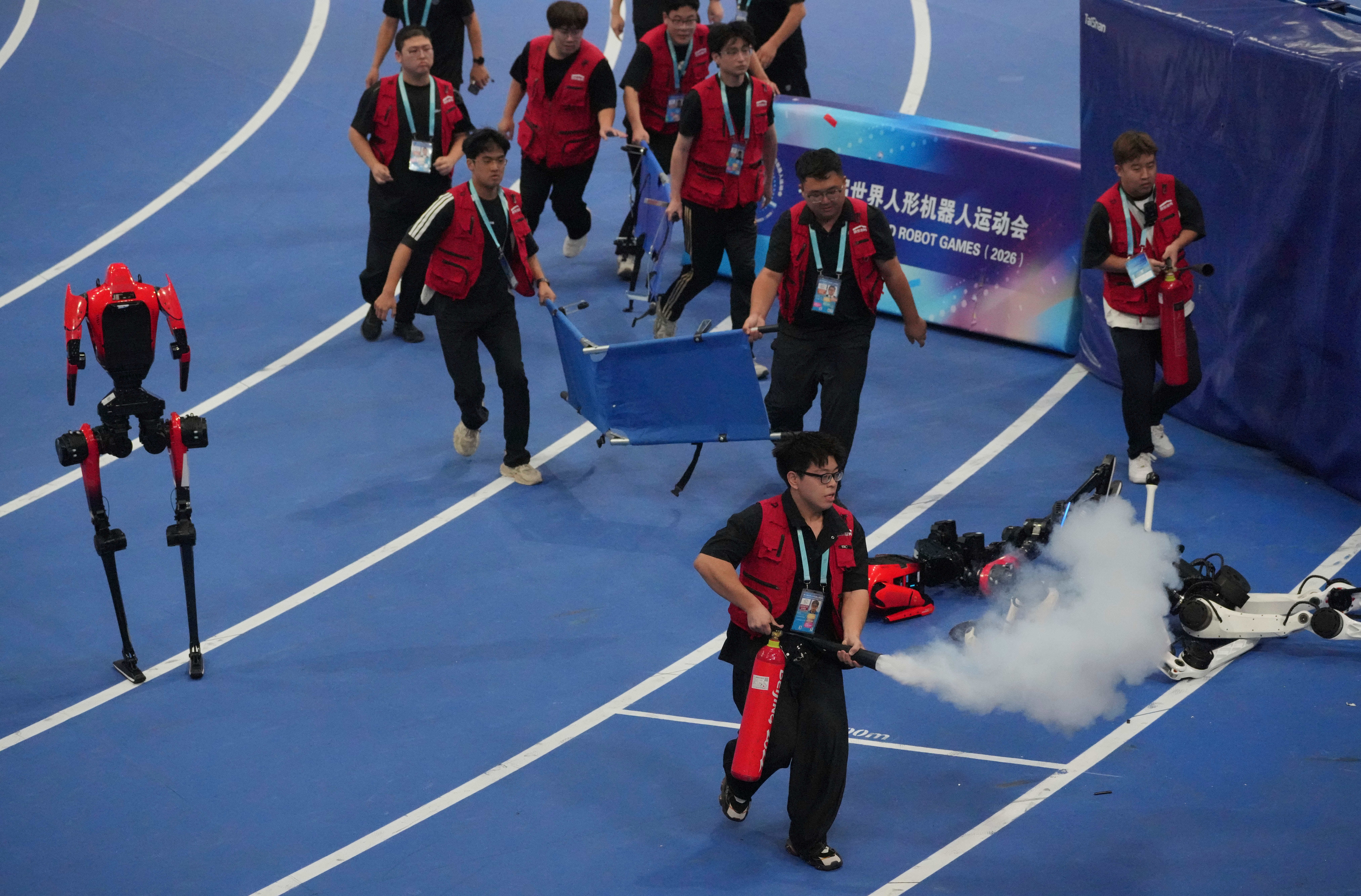 Officials extinguish a fire of a Humanoid robot after hitting the barrier at the end of the 100 meter final race during the World Humanoid Robot Games in Beijing, Wednesday, Aug. 26, 2026.