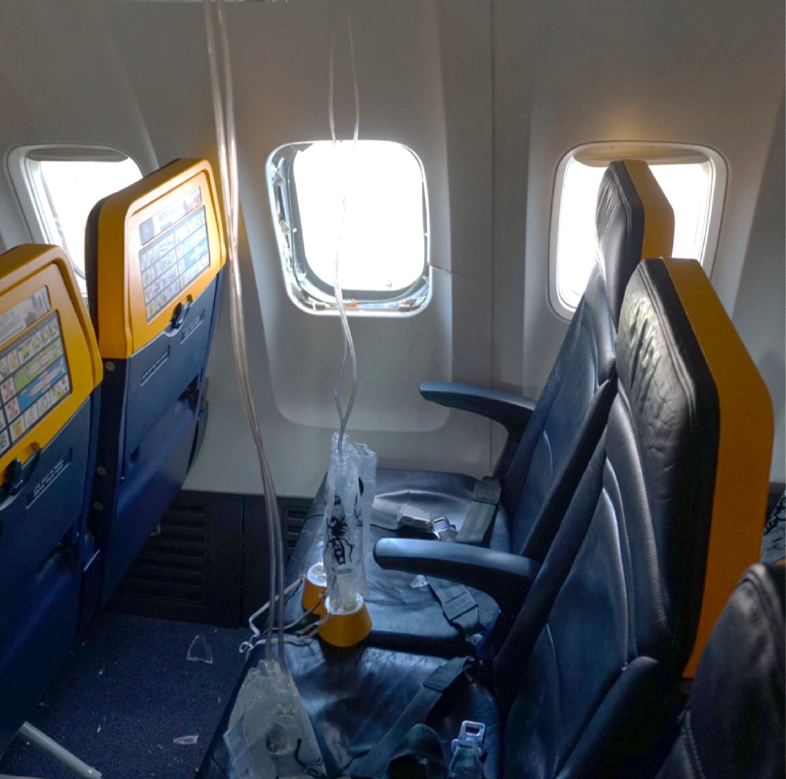 This undated photo provided by the National Transportation Safety Board on Thursday, Aug. 13, 2026, shows the shattered window on a Ryanair plane that was broken by a stray engine part shortly after takeoff, causing a man's head to be sucked into the hole.