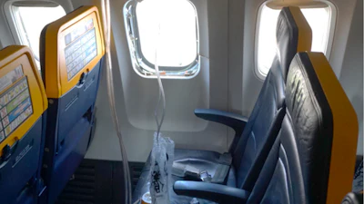This undated photo provided by the National Transportation Safety Board on Thursday, Aug. 13, 2026, shows the shattered window on a Ryanair plane that was broken by a stray engine part shortly after takeoff, causing a man's head to be sucked into the hole.